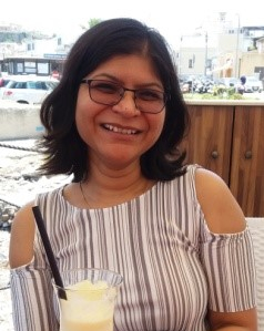 Young woman with mid length hair and glasses smiling at the camera